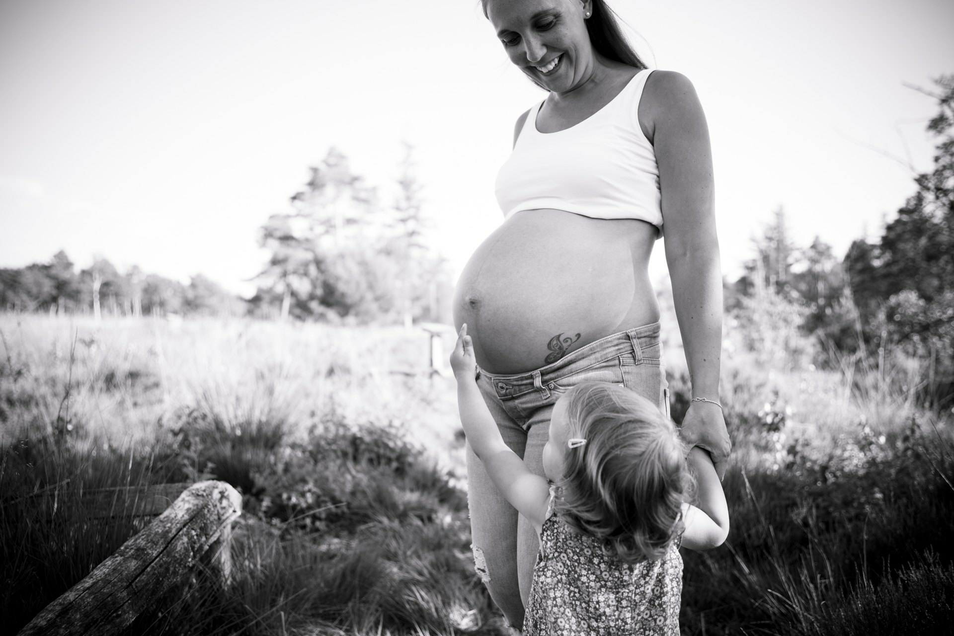 Babybauchfotografie mit Geschwisterkind: Zärtlicher Moment in Schwarz-Weiß